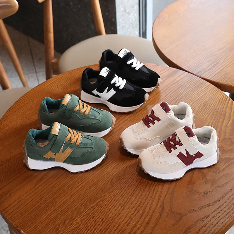 Four pairs of children's sneakers on a wooden table.